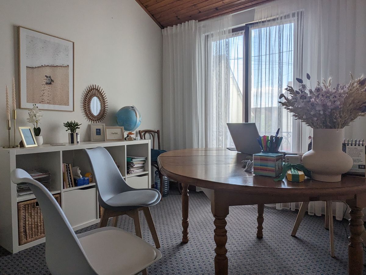 Le bureau de CAPerspectives à Houilles : une table ronde, deux chaises et une bibliothèque devant une grande fenêtre.